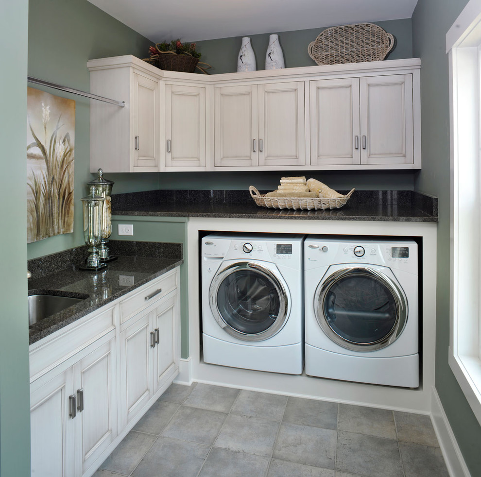 Immagine di una lavanderia multiuso classica con pareti verdi, pavimento grigio, lavello sottopiano, ante a filo, ante con finitura invecchiata, paraspruzzi marrone, lavatrice e asciugatrice affiancate e top multicolore