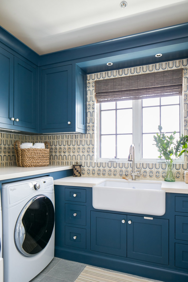 Idee per una grande sala lavanderia tropicale con lavello stile country, ante in stile shaker, ante blu, pareti multicolore, lavatrice e asciugatrice affiancate, pavimento grigio e top beige