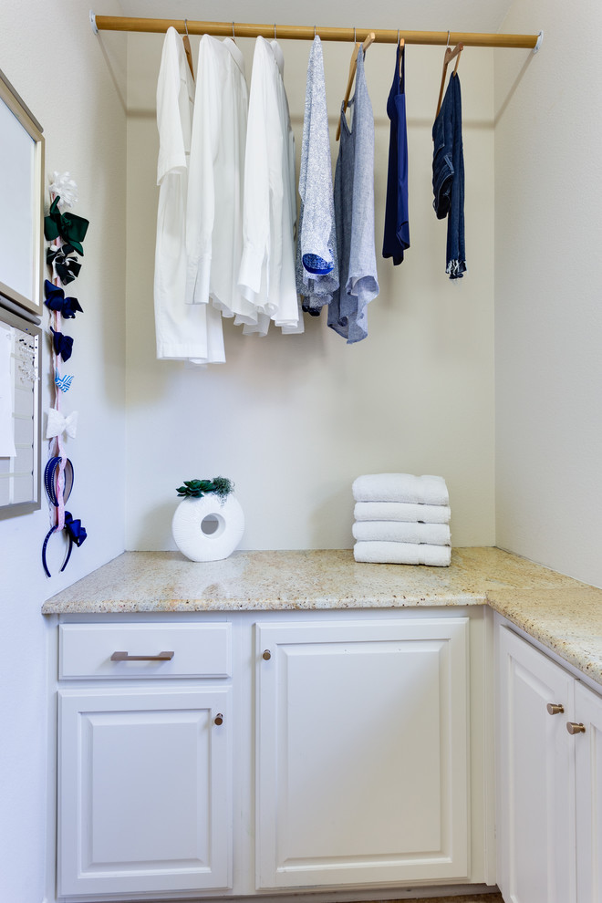 Inredning av en modern parallell tvättstuga enbart för tvätt, med luckor med upphöjd panel, vita skåp, granitbänkskiva, beige väggar och en tvättmaskin och torktumlare bredvid varandra