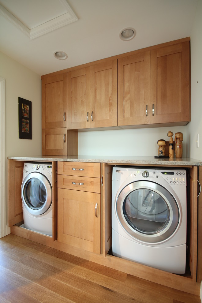 Design ideas for a traditional utility room in DC Metro with shaker cabinets, white walls, light hardwood flooring, a side by side washer and dryer and medium wood cabinets.