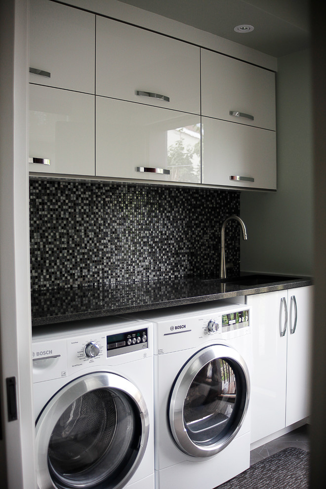 モントリオールにある小さなおしゃれな洗濯室 (I型、ドロップインシンク、フラットパネル扉のキャビネット、白いキャビネット、オニキスカウンター、ベージュの壁、左右配置の洗濯機・乾燥機) の写真