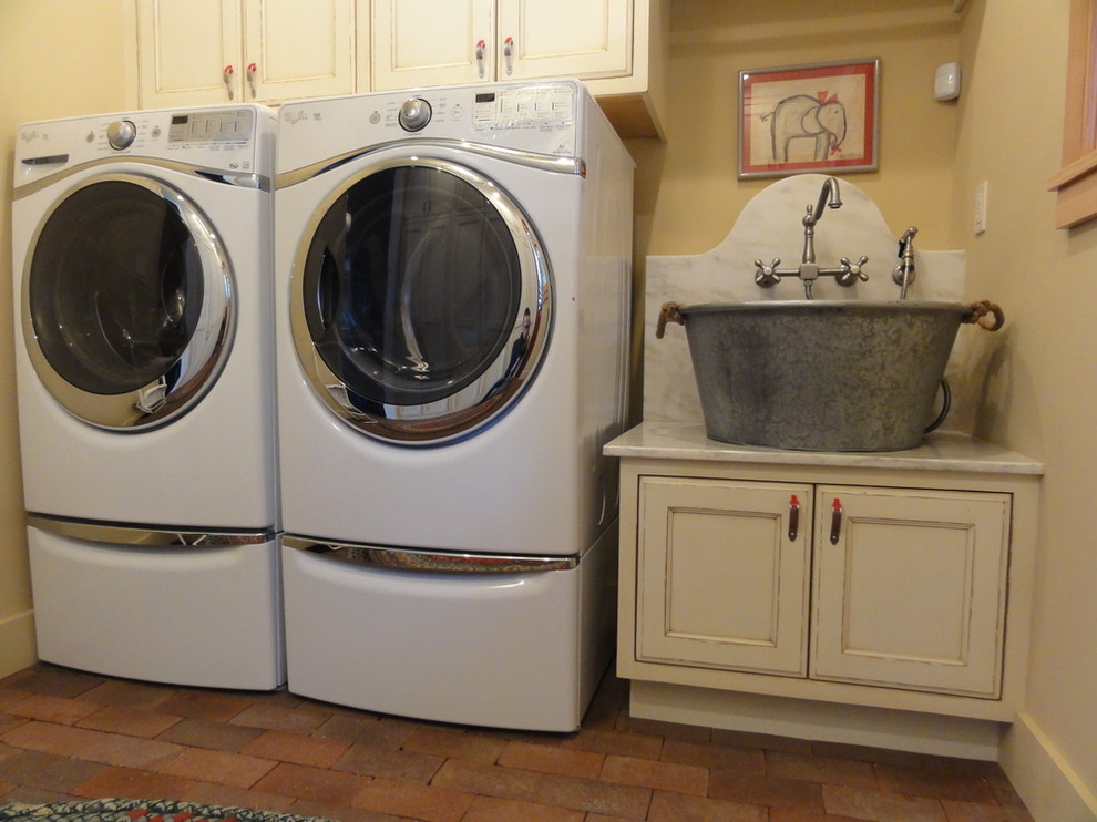 Immagine di una piccola sala lavanderia chic con lavello a vasca singola, ante con riquadro incassato, top in marmo, pareti gialle, pavimento in mattoni, lavatrice e asciugatrice affiancate e ante beige