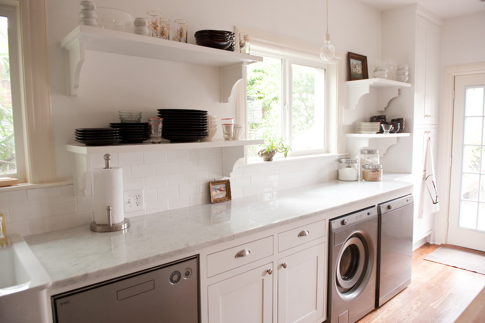 Foto di una lavanderia multiuso classica con ante bianche, pareti bianche, parquet chiaro, lavatrice e asciugatrice affiancate e top bianco