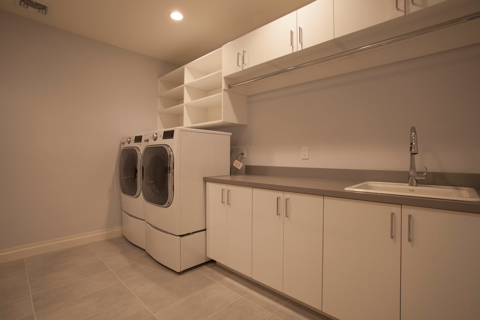 Mid-sized elegant single-wall ceramic tile and beige floor dedicated laundry room photo in New York with a drop-in sink, flat-panel cabinets, white cabinets, quartz countertops, white walls and a side-by-side washer/dryer