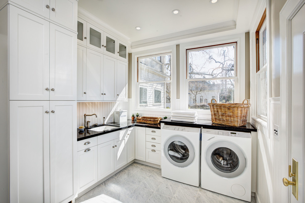 Idéer för lantliga l-formade tvättstugor enbart för tvätt, med en undermonterad diskho, vita skåp, beige väggar, en tvättmaskin och torktumlare bredvid varandra och skåp i shakerstil