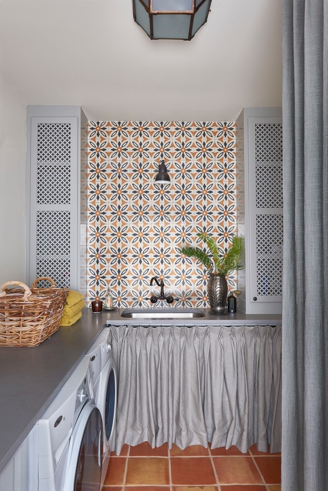 Inspiration for a medium sized bohemian l-shaped separated utility room in Orlando with a submerged sink, grey cabinets, composite countertops, white walls, terracotta flooring, a side by side washer and dryer and grey worktops.