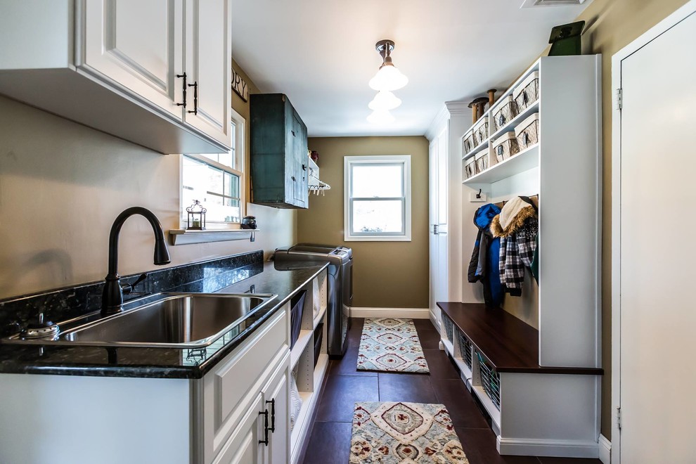 Large classic galley utility room in Birmingham with a built-in sink, raised-panel cabinets, white cabinets, granite worktops, beige walls, a side by side washer and dryer, concrete flooring and brown floors.