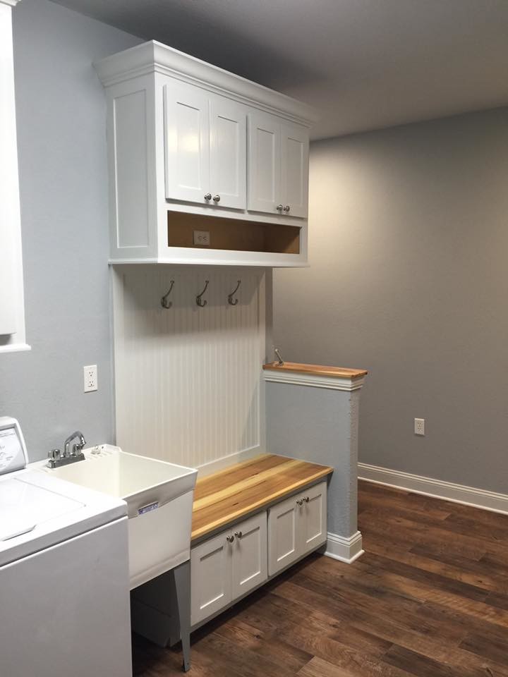 Exempel på ett mellanstort klassiskt linjärt grovkök, med en allbänk, skåp i shakerstil, vita skåp, grå väggar, mellanmörkt trägolv, en tvättmaskin och torktumlare bredvid varandra och brunt golv