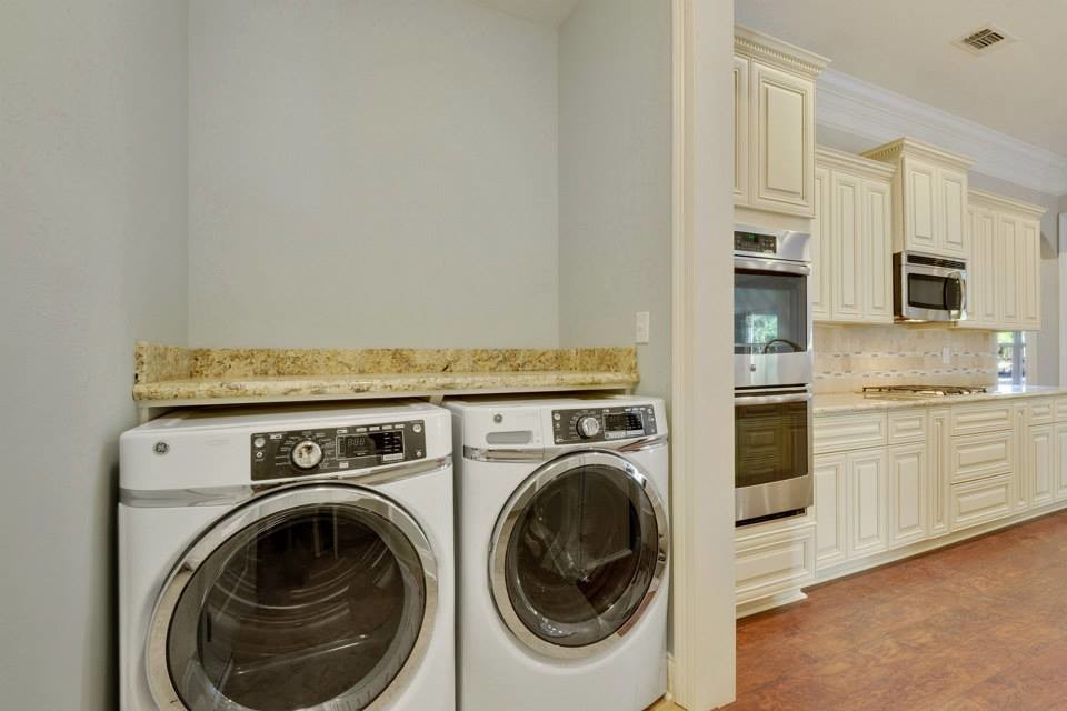 ニューオリンズにあるおしゃれなランドリールーム (I型、グレーの壁、リノリウムの床、左右配置の洗濯機・乾燥機、茶色い床) の写真