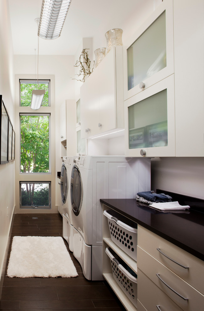 Trendy galley porcelain tile dedicated laundry room photo in Jacksonville with flat-panel cabinets, white cabinets, solid surface countertops, white walls and a side-by-side washer/dryer