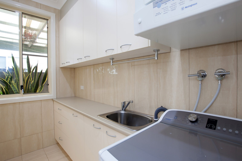 Zweizeilige, Mittelgroße Moderne Waschküche mit Waschbecken, Travertin und Waschmaschine und Trockner gestapelt in Sydney