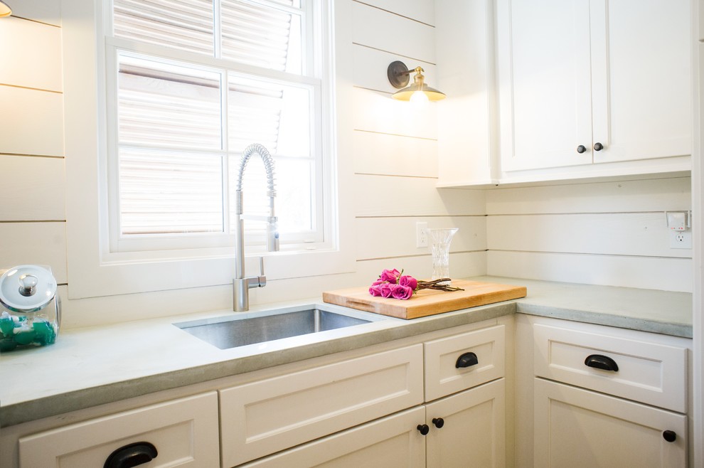 Idéer för mellanstora lantliga u-formade grått tvättstugor enbart för tvätt, med en undermonterad diskho, luckor med infälld panel, vita skåp, bänkskiva i betong, vita väggar och en tvättmaskin och torktumlare bredvid varandra