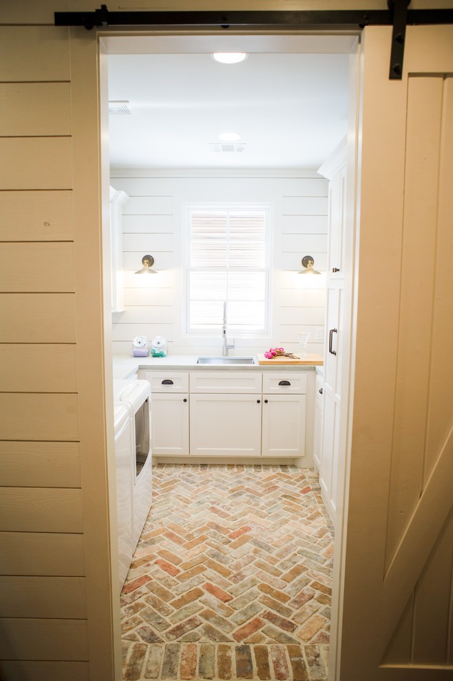 Inspiration for a mid-sized country u-shaped brick floor and beige floor dedicated laundry room remodel in Houston with an undermount sink, recessed-panel cabinets, white cabinets, white walls, a side-by-side washer/dryer, concrete countertops and gray countertops