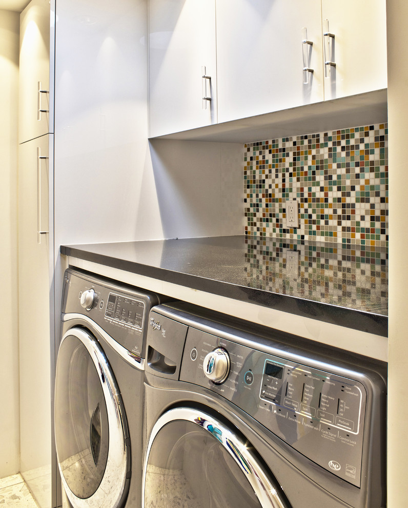 Idéer för en liten 50 tals linjär tvättstuga enbart för tvätt, med släta luckor, vita skåp, granitbänkskiva, vita väggar, marmorgolv och en tvättmaskin och torktumlare bredvid varandra