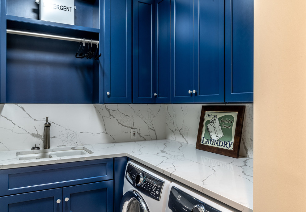 Kleine Klassische Waschküche mit Doppelwaschbecken, Schrankfronten mit vertiefter Füllung, blauen Schränken, Quarzit-Arbeitsplatte, Waschmaschine und Trockner nebeneinander und weißer Arbeitsplatte in Charleston