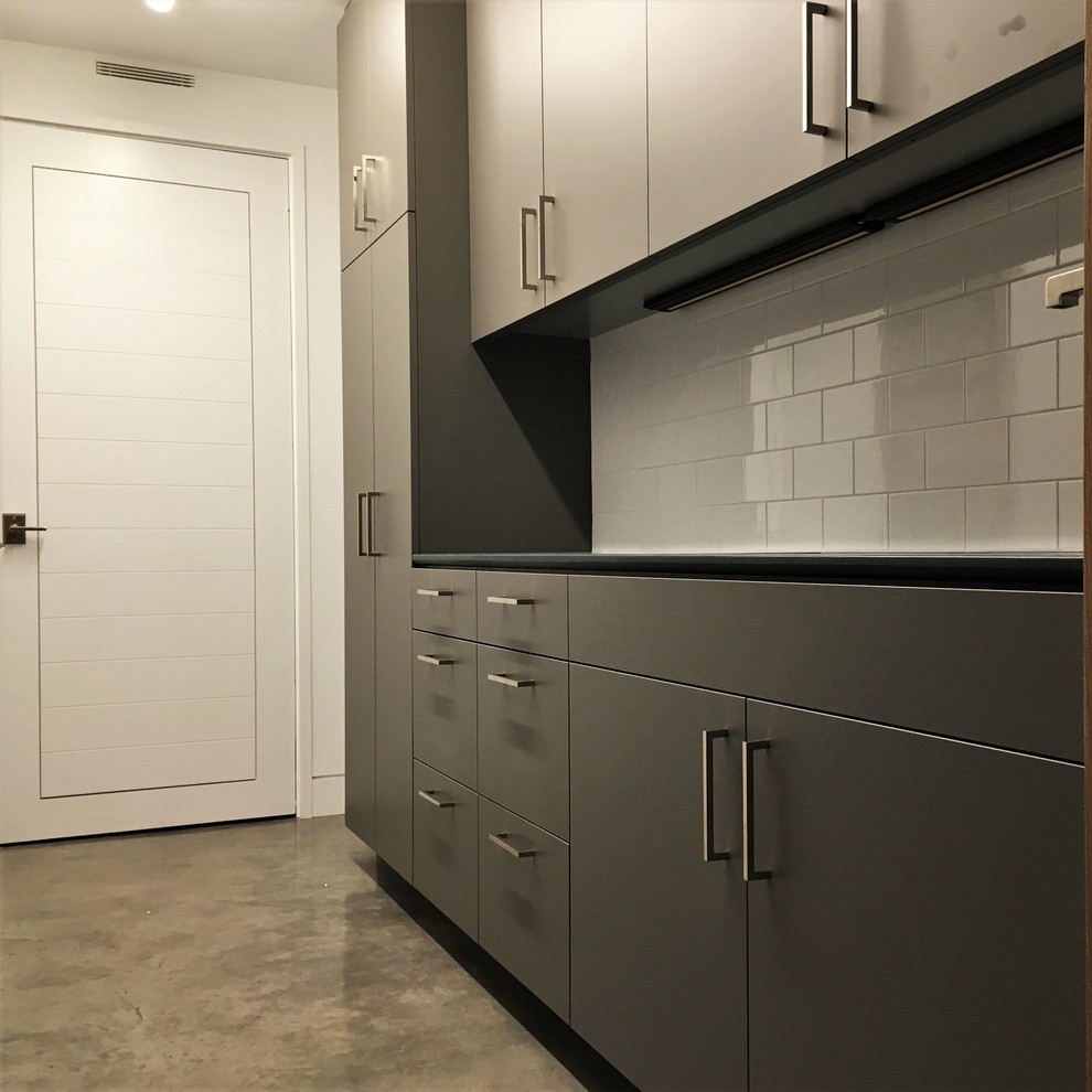Dedicated laundry room - mid-sized contemporary galley concrete floor and gray floor dedicated laundry room idea in Other with an integrated sink, flat-panel cabinets, gray cabinets, concrete countertops, white walls and a side-by-side washer/dryer