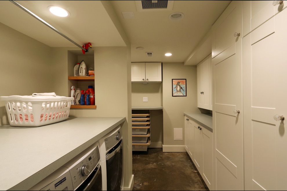 This is an example of a large traditional galley separated utility room in Portland with white cabinets, concrete flooring and a side by side washer and dryer.