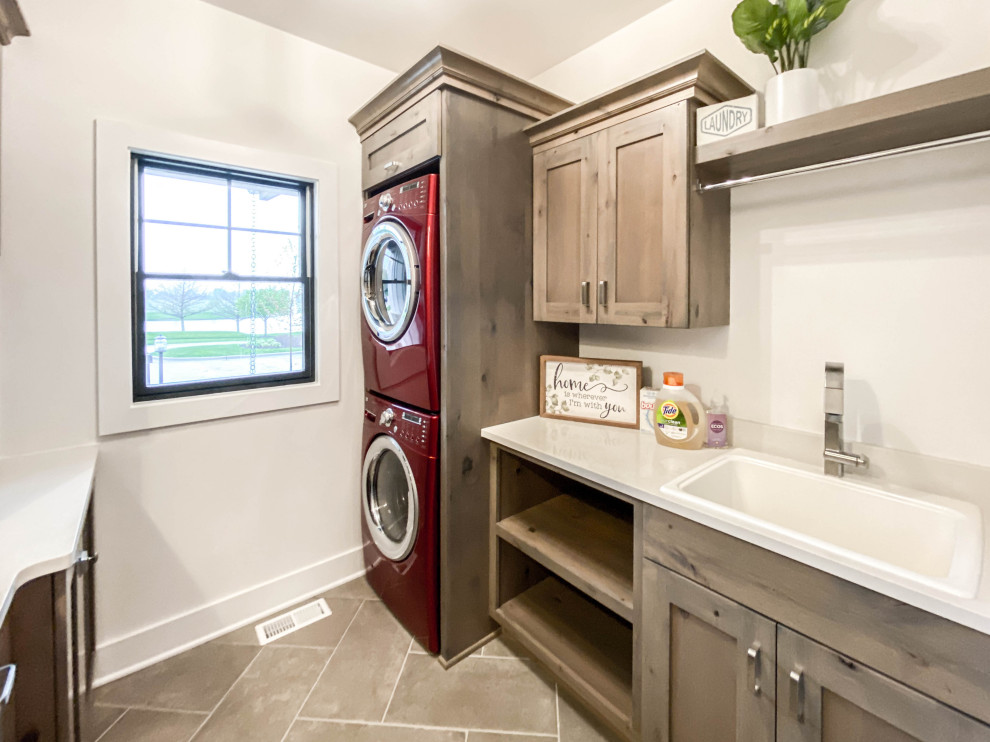 Design ideas for a medium sized country separated utility room in Chicago with a belfast sink, shaker cabinets, distressed cabinets, engineered stone countertops, a stacked washer and dryer and white worktops.