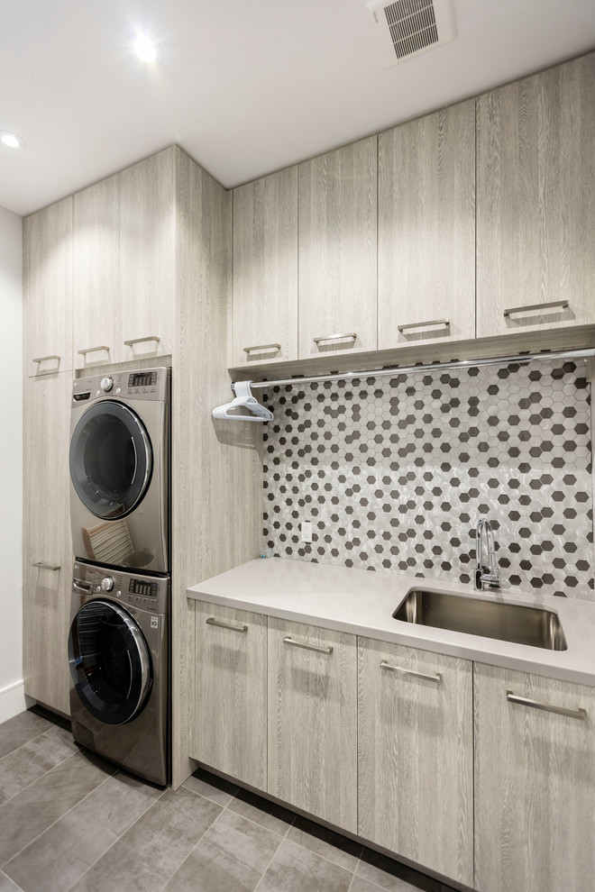 Idéer för att renovera en stor linjär tvättstuga enbart för tvätt, med en undermonterad diskho, släta luckor, bänkskiva i kvarts, vita väggar, klinkergolv i porslin, en tvättpelare och grå skåp