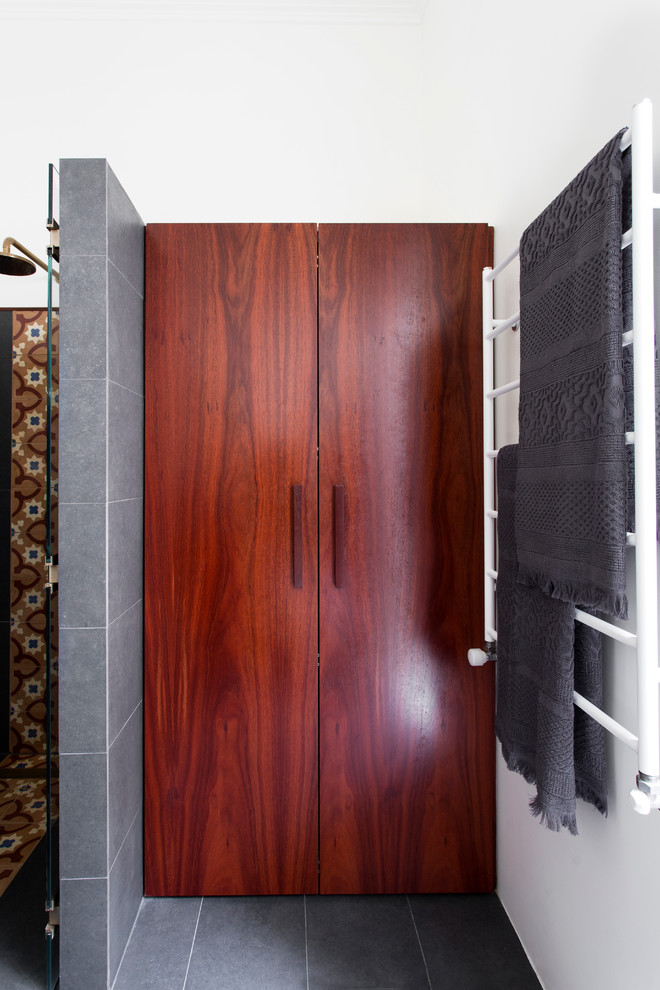Пример оригинального дизайна: маленькая универсальная комната в стиле фьюжн с темными деревянными фасадами, полом из керамогранита и со скрытой стиральной машиной для на участке и в саду