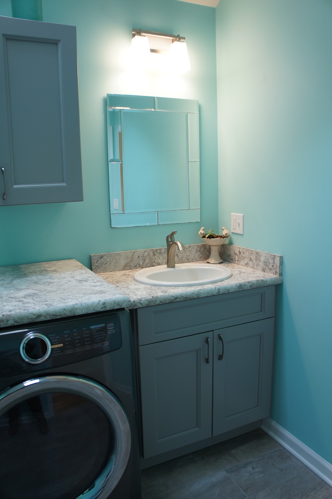 ニューヨークにあるお手頃価格の中くらいなトランジショナルスタイルのおしゃれな家事室 (I型、ドロップインシンク、シェーカースタイル扉のキャビネット、グレーのキャビネット、ラミネートカウンター、青い壁、セラミックタイルの床、左右配置の洗濯機・乾燥機) の写真