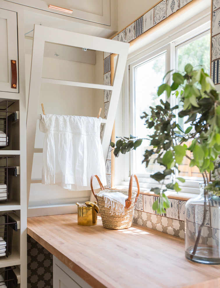 Idée de décoration pour une buanderie chalet multi-usage et de taille moyenne avec un placard à porte shaker, des portes de placard grises, un plan de travail en bois, un mur blanc, parquet foncé et des machines superposées.