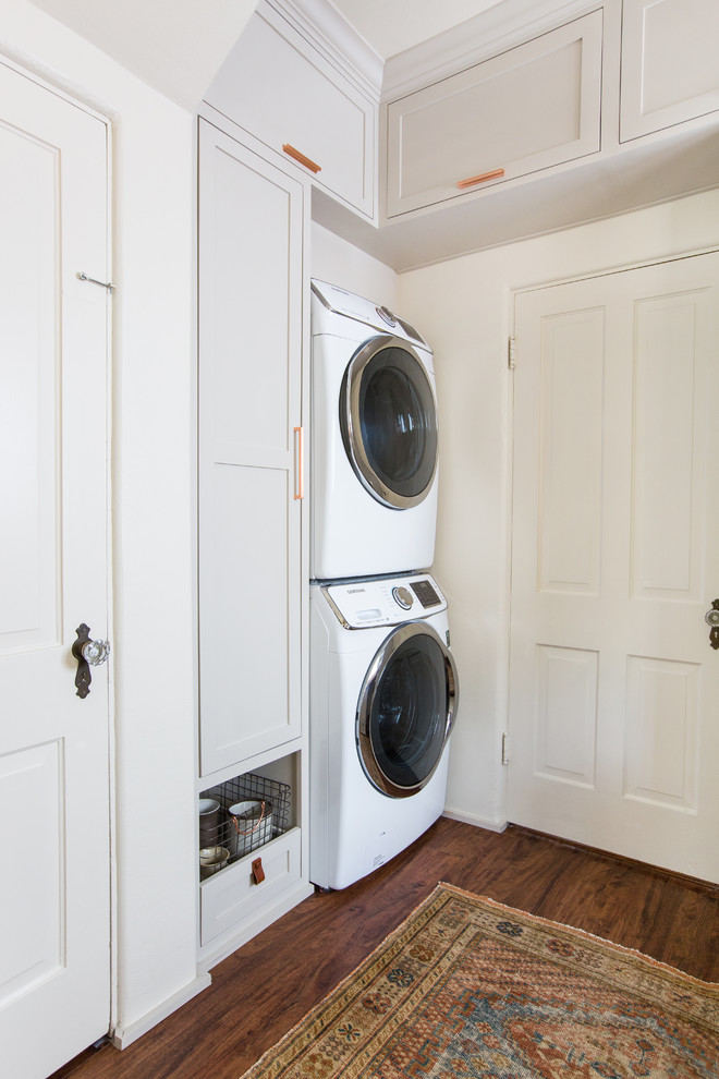 Foto de lavadero multiusos clásico renovado de tamaño medio con armarios estilo shaker, puertas de armario grises, encimera de madera, paredes blancas, suelo de madera oscura y lavadora y secadora apiladas
