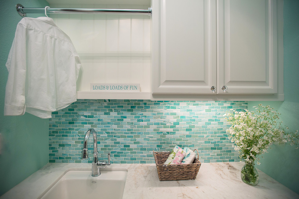 Eklektisk inredning av en mellanstor parallell tvättstuga enbart för tvätt, med en undermonterad diskho, luckor med upphöjd panel, vita skåp, marmorbänkskiva, blå väggar, klinkergolv i porslin, en tvättpelare och beiget golv