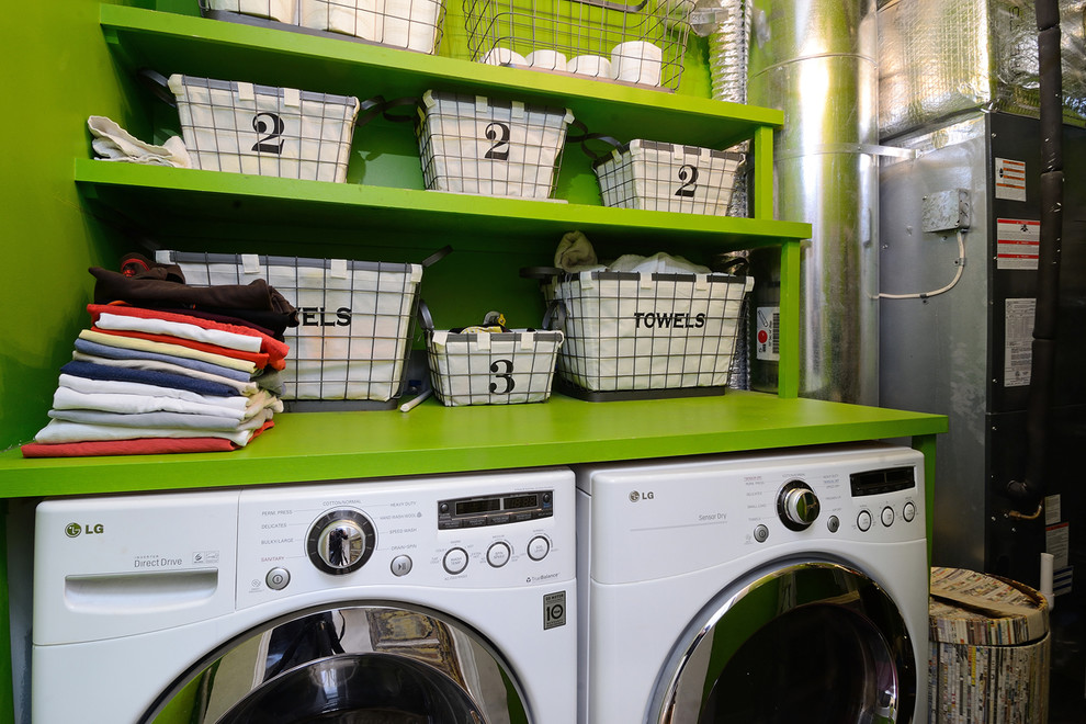 This is an example of an eclectic utility room in New York with open cabinets, green cabinets, green walls, a side by side washer and dryer and green worktops.