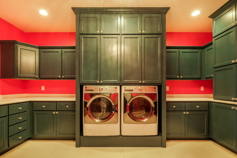 Rustik inredning av en mycket stor u-formad tvättstuga enbart för tvätt, med luckor med infälld panel, gröna skåp, bänkskiva i kvartsit, klinkergolv i keramik, en tvättmaskin och torktumlare bredvid varandra och orange väggar
