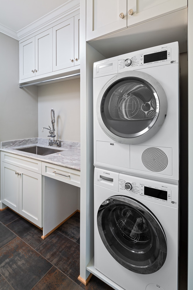 Inspiration for a medium sized traditional single-wall separated utility room in Other with a submerged sink, shaker cabinets, white cabinets, granite worktops, grey walls, ceramic flooring, a stacked washer and dryer and grey worktops.