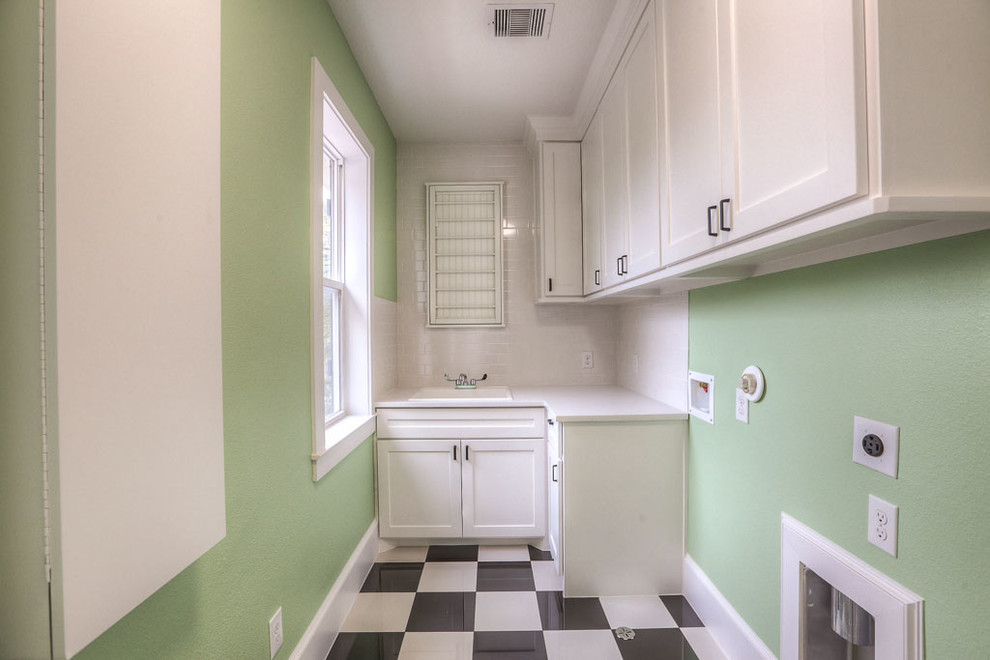 Mid-sized transitional l-shaped linoleum floor dedicated laundry room photo in Orange County with a drop-in sink, shaker cabinets, white cabinets, solid surface countertops and green walls