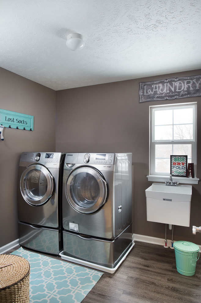 Immagine di una sala lavanderia classica di medie dimensioni con lavello da incasso, top in superficie solida, pareti marroni, parquet scuro, lavatrice e asciugatrice affiancate e pavimento marrone