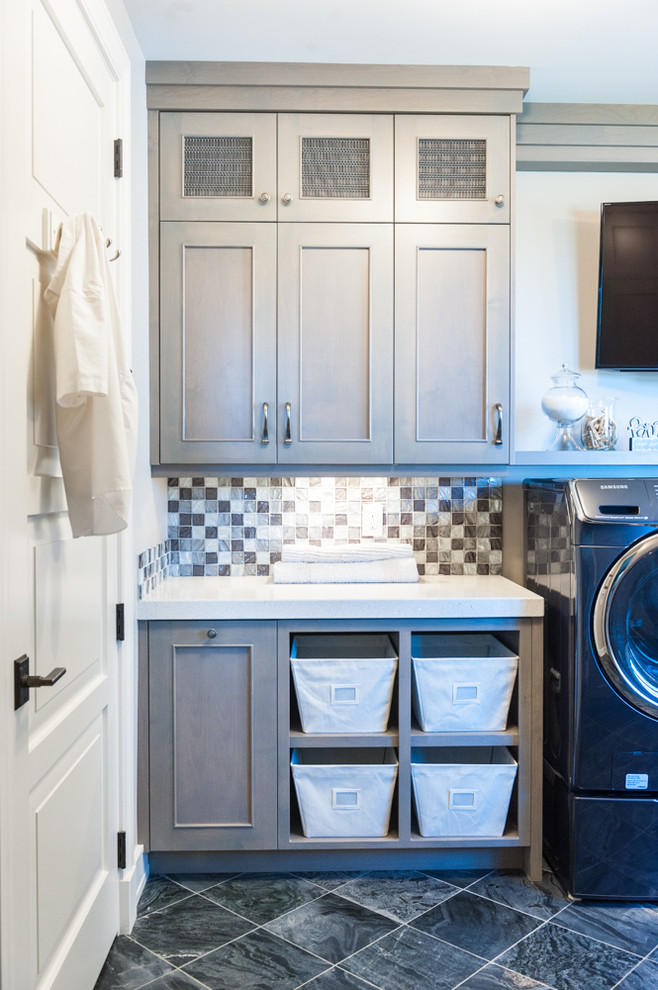 Modelo de cuarto de lavado de galera con armarios con paneles lisos, lavadora y secadora juntas y puertas de armario grises
