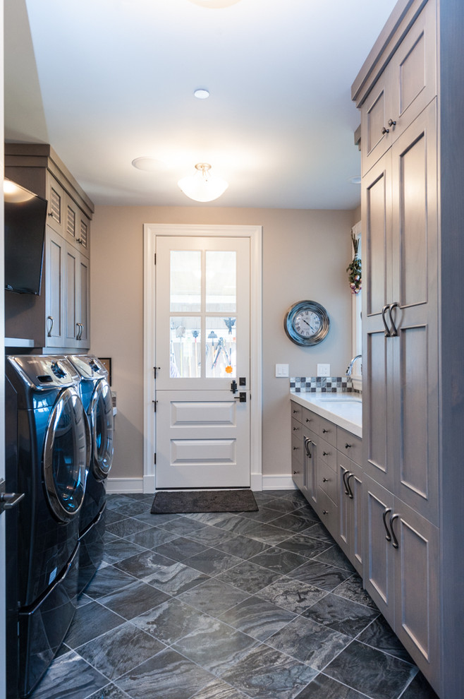 Foto de cuarto de lavado de galera con armarios con paneles lisos, lavadora y secadora juntas y puertas de armario grises