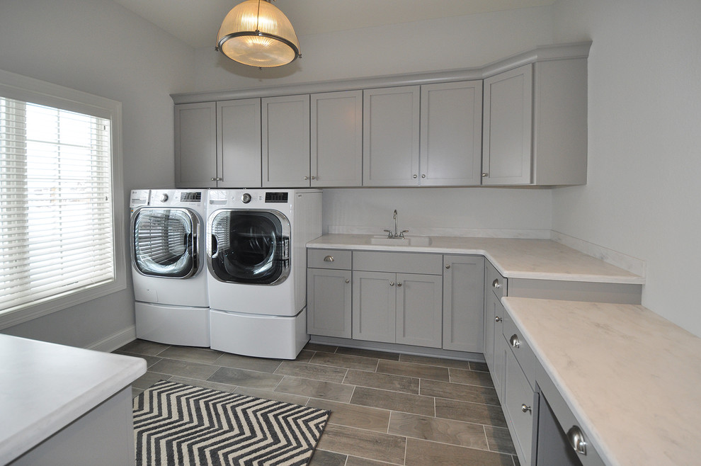 Idéer för mycket stora eklektiska u-formade tvättstugor enbart för tvätt, med en undermonterad diskho, luckor med infälld panel, grå skåp, marmorbänkskiva, grå väggar, klinkergolv i keramik och en tvättmaskin och torktumlare bredvid varandra
