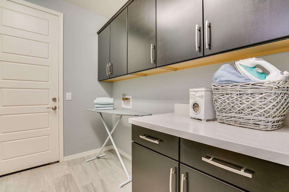Immagine di una sala lavanderia minimal di medie dimensioni con ante lisce, ante nere, top in superficie solida, pareti grigie, pavimento con piastrelle in ceramica e pavimento grigio