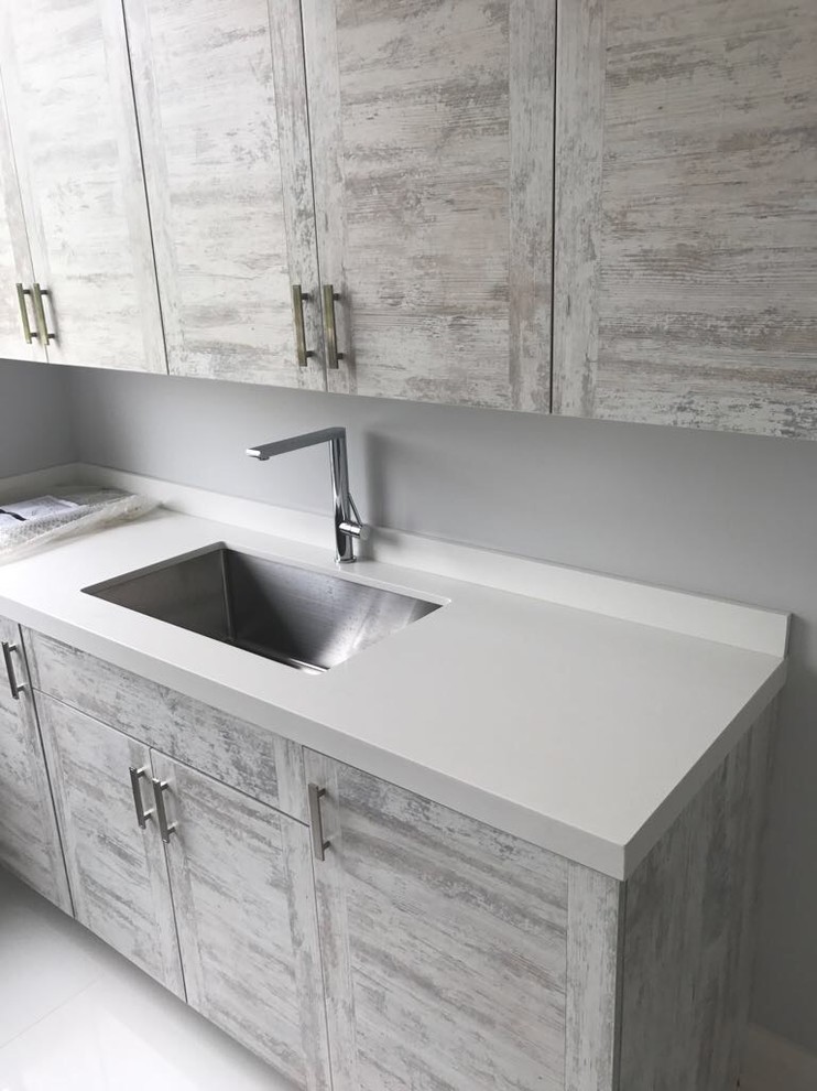 Laundry room - modern laundry room idea in Toronto with an undermount sink, flat-panel cabinets, distressed cabinets and gray walls