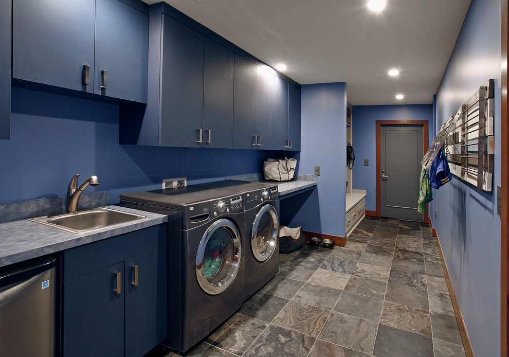 Esempio di un'ampia lavanderia multiuso chic con lavello da incasso, ante lisce, ante blu, top in laminato, pareti blu, pavimento con piastrelle in ceramica e lavatrice e asciugatrice affiancate