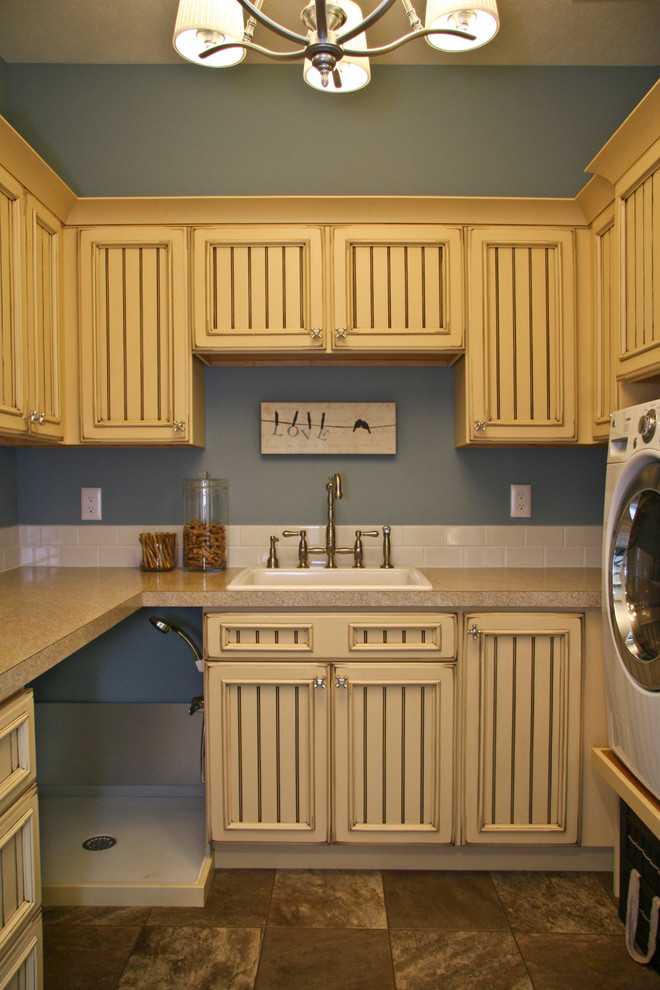 Inredning av ett klassiskt stort u-format grovkök, med en nedsänkt diskho, luckor med infälld panel, gula skåp, bänkskiva i koppar, blå väggar, skiffergolv och en tvättmaskin och torktumlare bredvid varandra