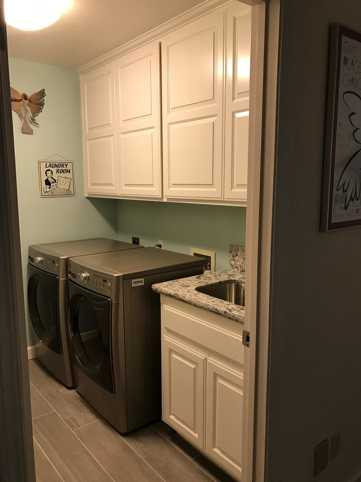 Inspiration for a medium sized traditional single-wall separated utility room in Santa Barbara with a submerged sink, raised-panel cabinets, white cabinets, granite worktops, blue walls, laminate floors, a side by side washer and dryer and grey floors.