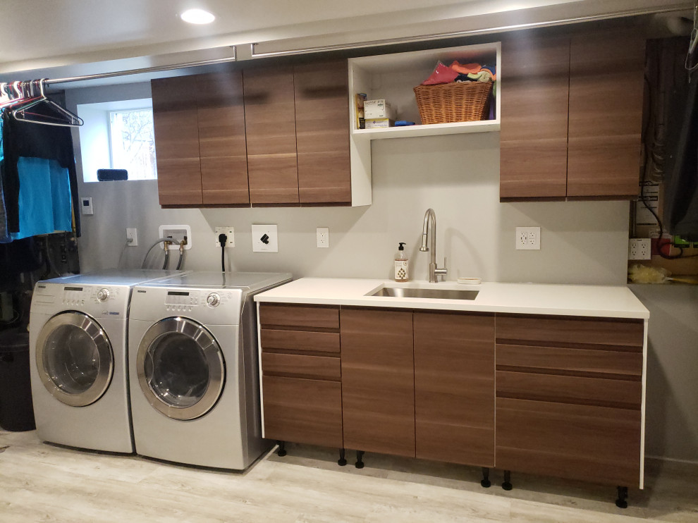 Inspiration for a large modern galley utility room in Edmonton with a submerged sink, flat-panel cabinets, medium wood cabinets, engineered stone countertops, grey walls, vinyl flooring, a side by side washer and dryer and white worktops.