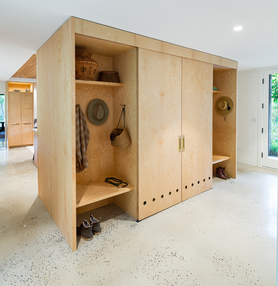 Foto di una lavanderia multiuso minimalista con ante lisce, ante in legno chiaro, top in legno, pavimento in cemento, lavatrice e asciugatrice nascoste e pavimento grigio