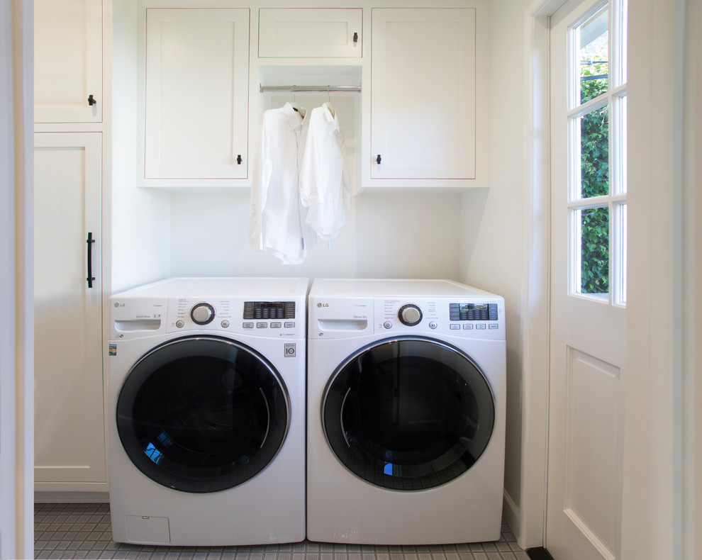 Einzeilige, Kleine Klassische Waschküche mit Schrankfronten im Shaker-Stil, weißen Schränken, weißer Wandfarbe, Waschmaschine und Trockner nebeneinander und grauem Boden in Los Angeles