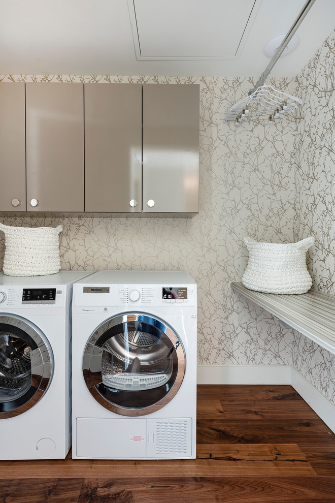 Inspiration for a modern separated utility room in Portland Maine with beige cabinets, multi-coloured walls, medium hardwood flooring and a side by side washer and dryer.
