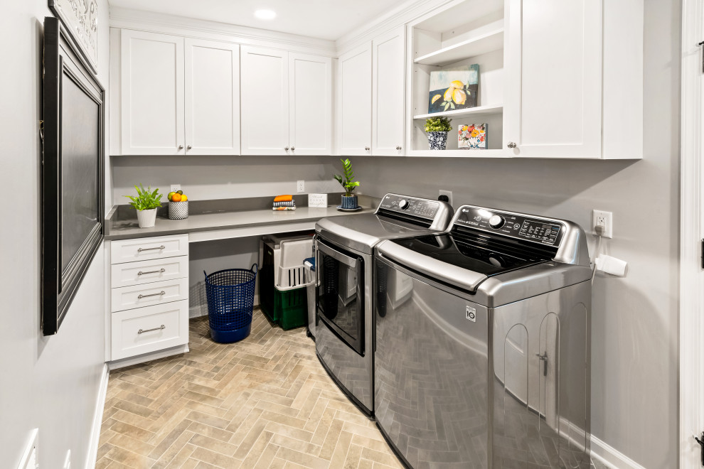 Utility room - mid-sized coastal l-shaped porcelain tile and gray floor utility room idea in Raleigh with shaker cabinets, white cabinets, quartz countertops, gray walls, a side-by-side washer/dryer and white countertops
