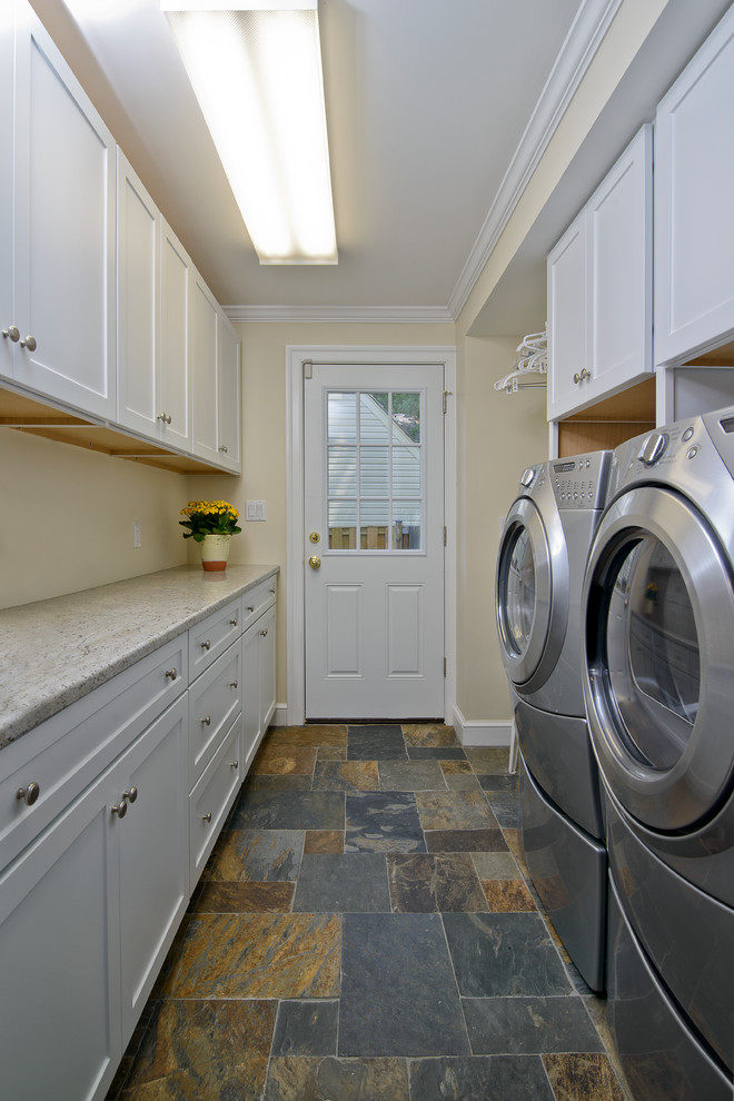 Immagine di una lavanderia multiuso chic con ante in stile shaker, ante bianche, pareti beige, pavimento in ardesia e lavatrice e asciugatrice affiancate