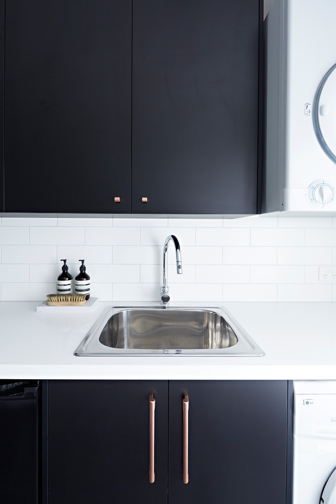 Idéer för mellanstora funkis linjära vitt tvättstugor enbart för tvätt, med en undermonterad diskho, svarta skåp, en tvättpelare, svart golv, bänkskiva i kvarts och vita väggar