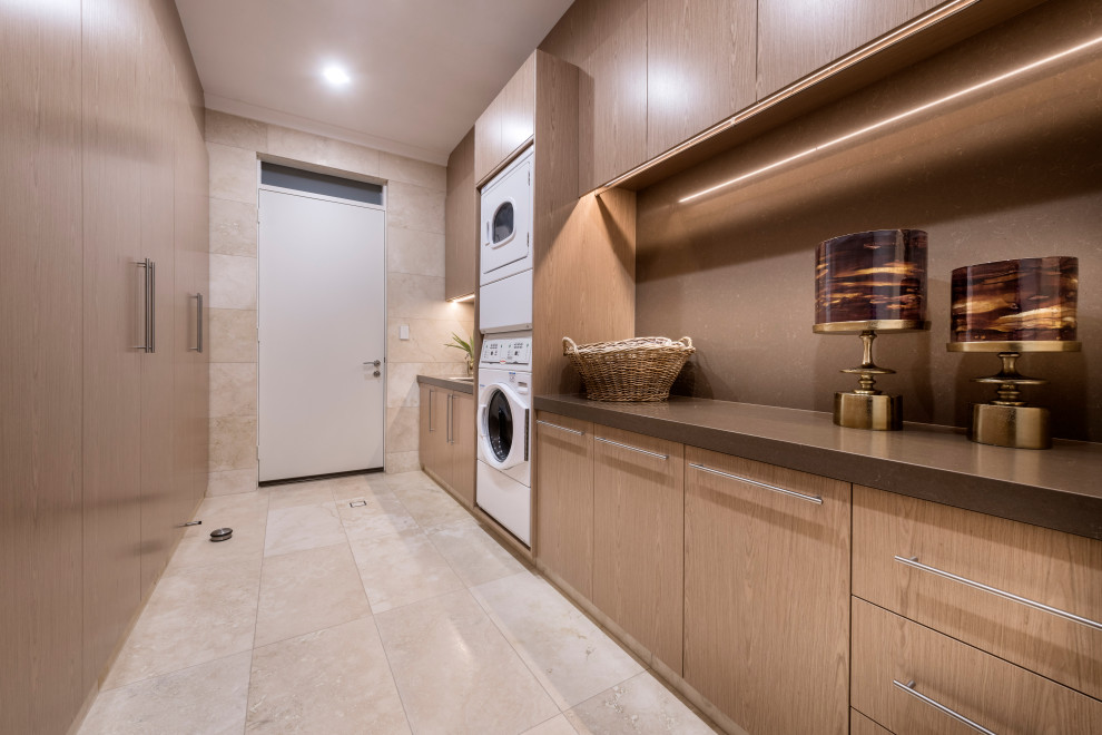 Modern inredning av en stor bruna parallell brunt tvättstuga enbart för tvätt, med en undermonterad diskho, luckor med infälld panel, skåp i ljust trä, bänkskiva i kvarts, beige väggar, travertin golv, en tvättpelare och beiget golv