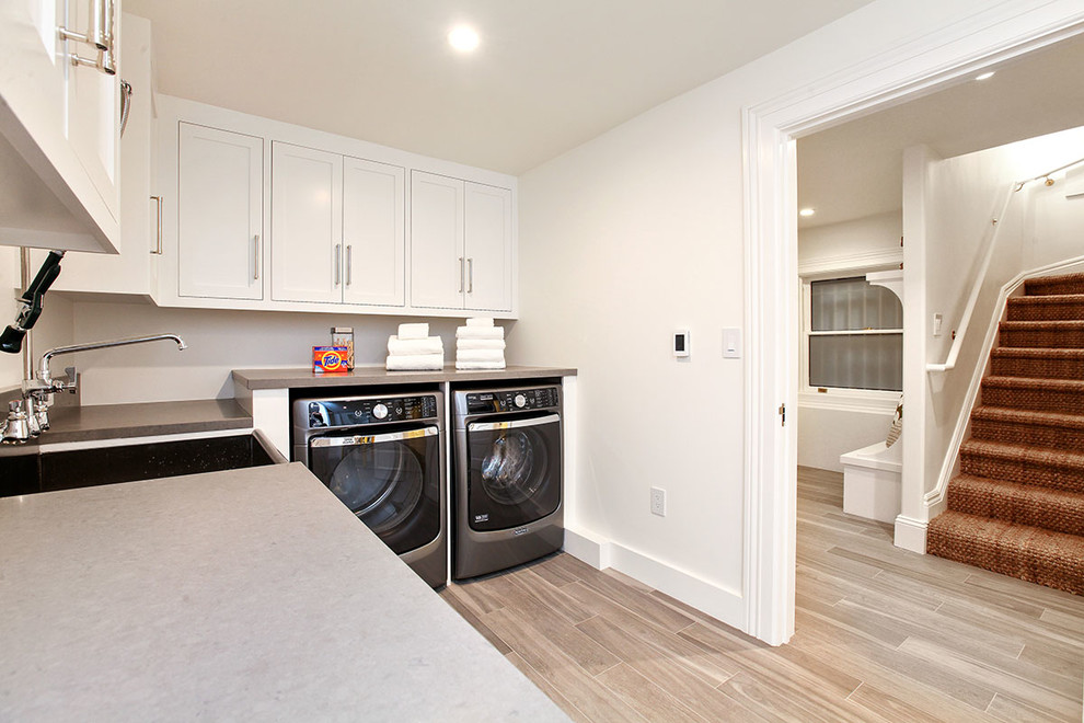 Example of a huge transitional l-shaped porcelain tile and beige floor dedicated laundry room design in San Francisco with recessed-panel cabinets, white cabinets, quartz countertops, white walls, a side-by-side washer/dryer and an utility sink